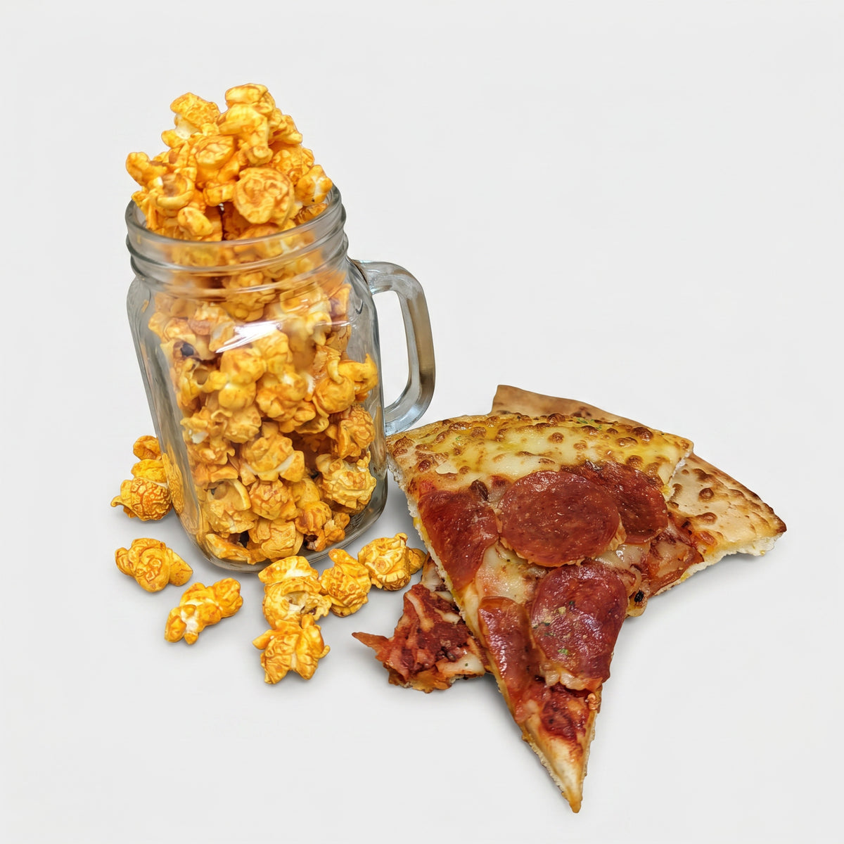 Mason jar filled with popcorn and a slice of pepperoni pizza on a light gray background