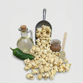 Popcorn with a bottle of oil, a jalapeño pepper, and a scoop on a light gray background