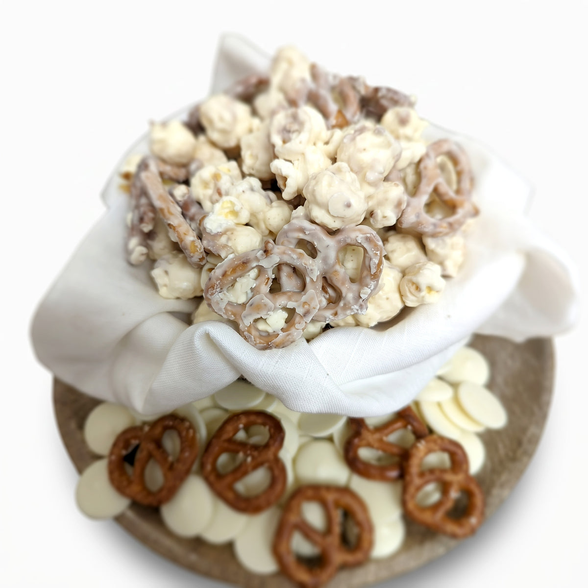 Assorted snack mix with pretzels and popcorn in a white bowl on a white background