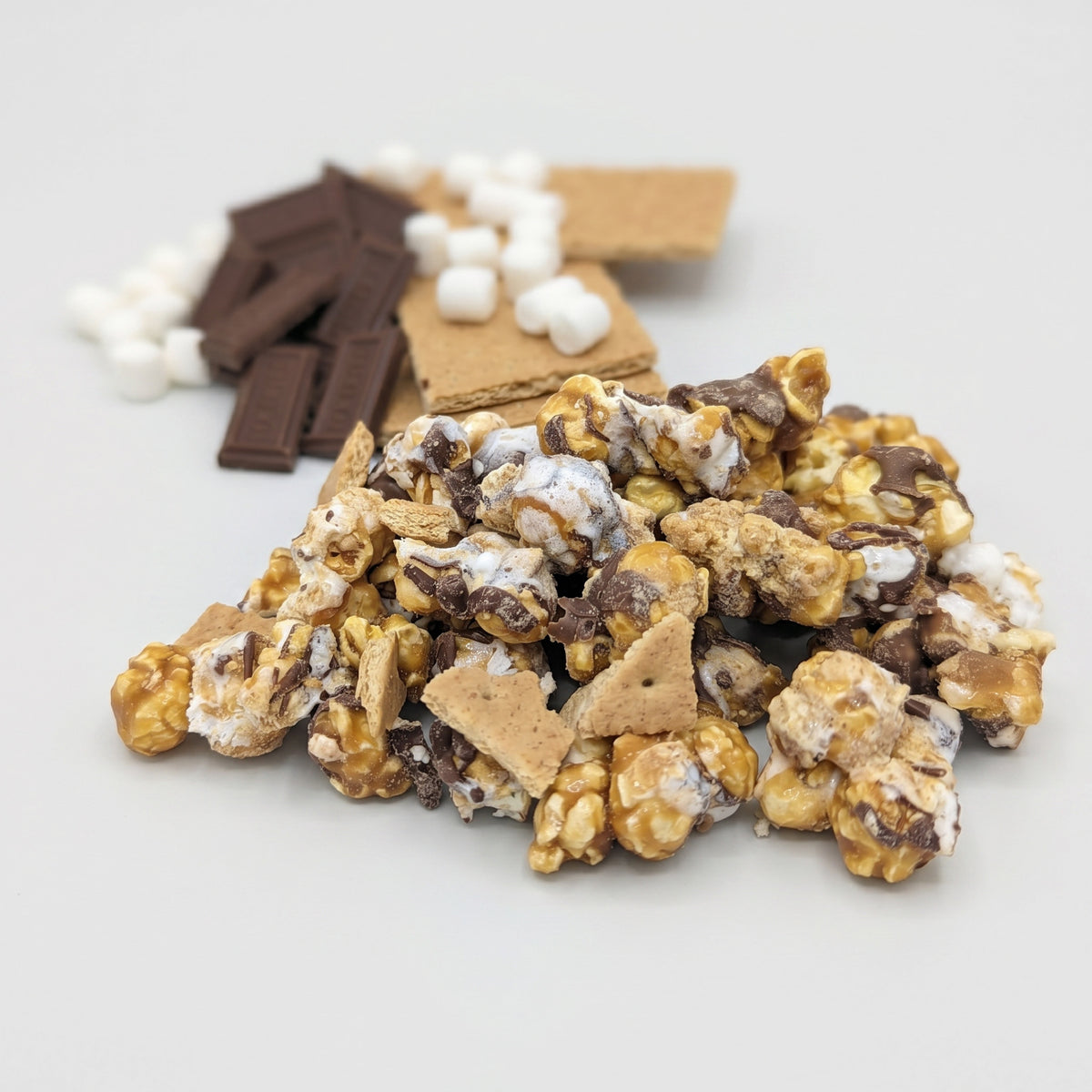 S'mores popcorn with graham crackers, chocolate, and marshmallows on a light background